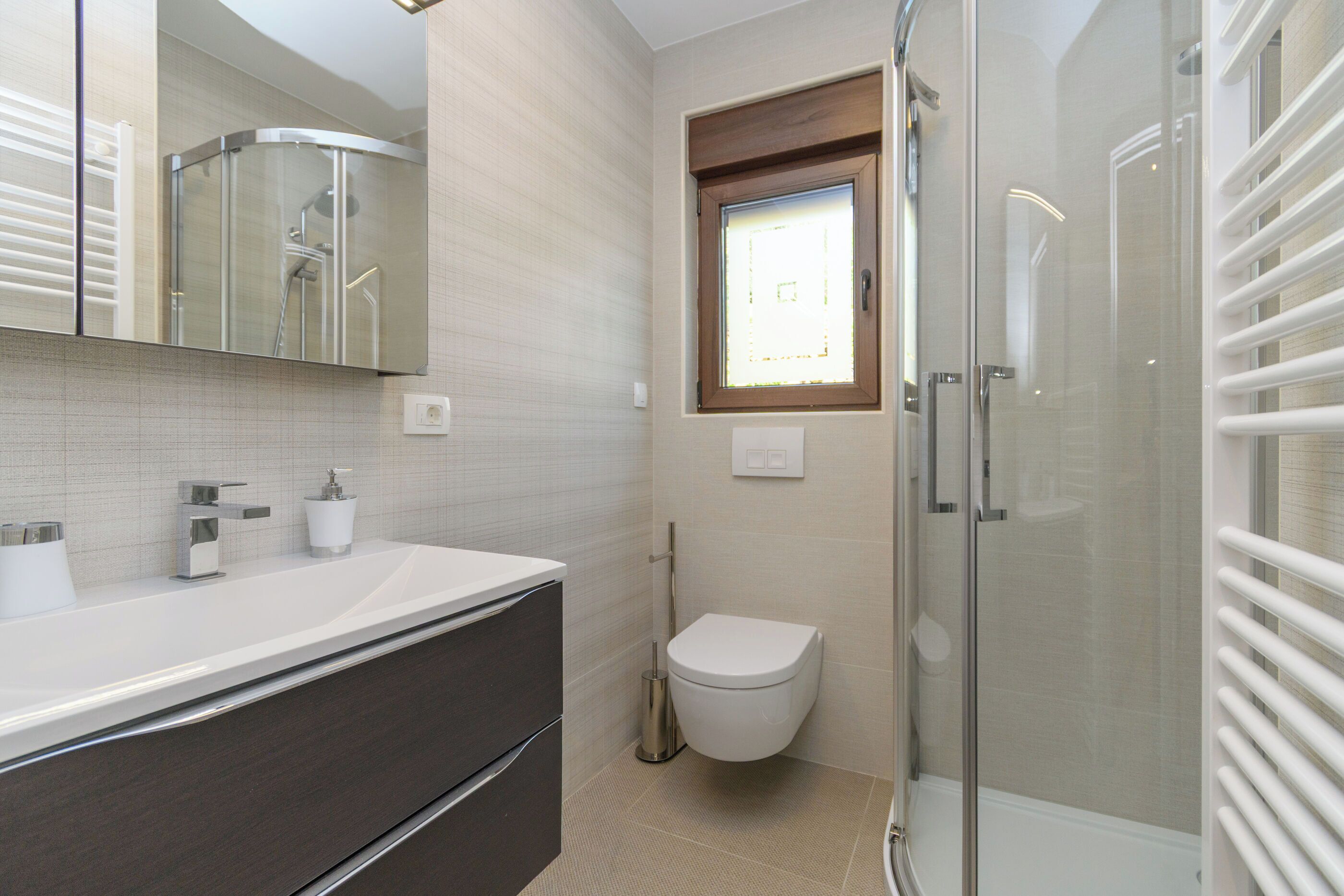 A modern bathroom with a shower, toilet, and vanity.
