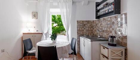 A compact kitchen with a dining area, a small sink, and a coffee machine.