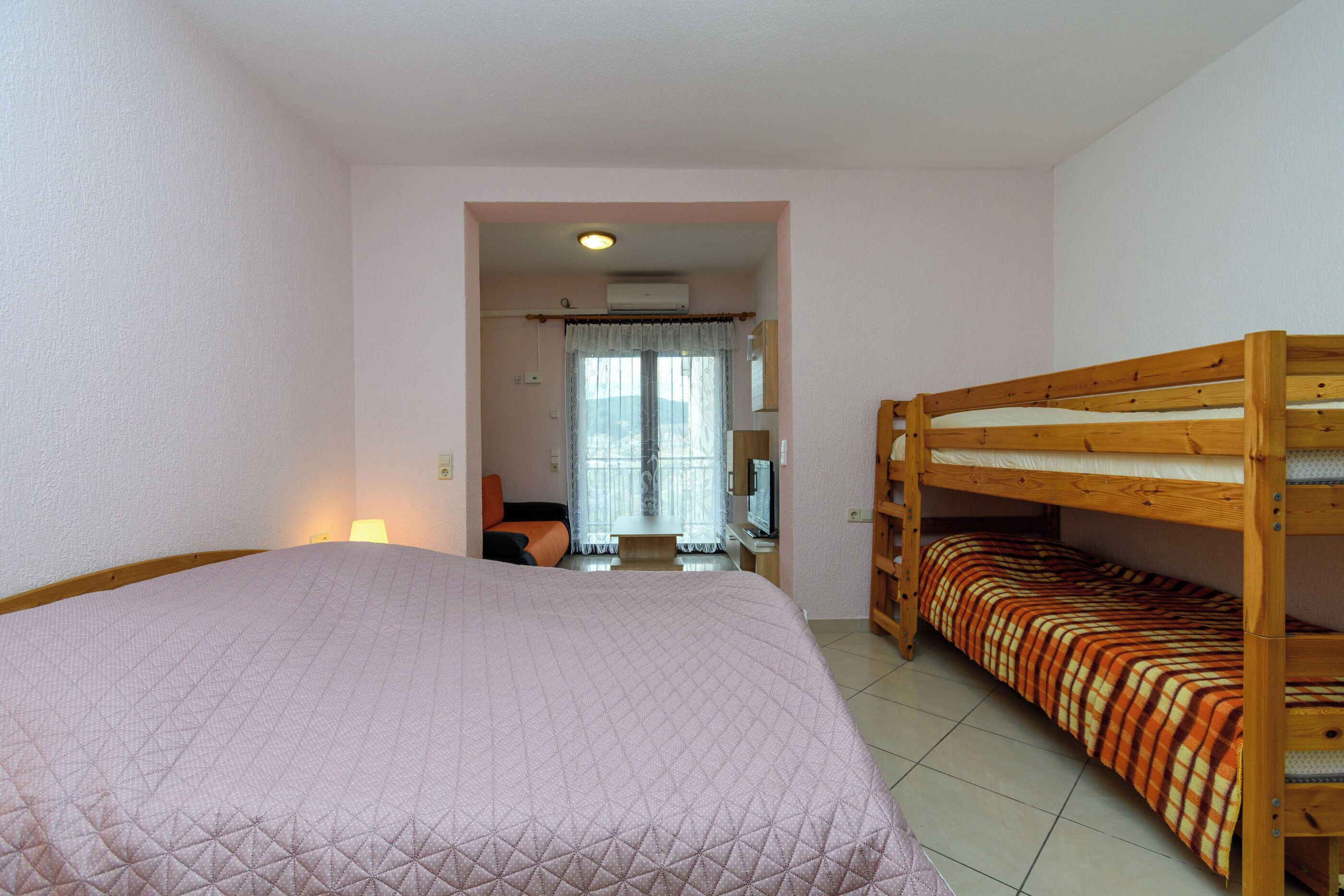 Ein Schlafzimmer mit einem großen Bett, einem Stockbett, einem Schreibtisch mit Stuhl und einem Fenster mit Vorhängen.