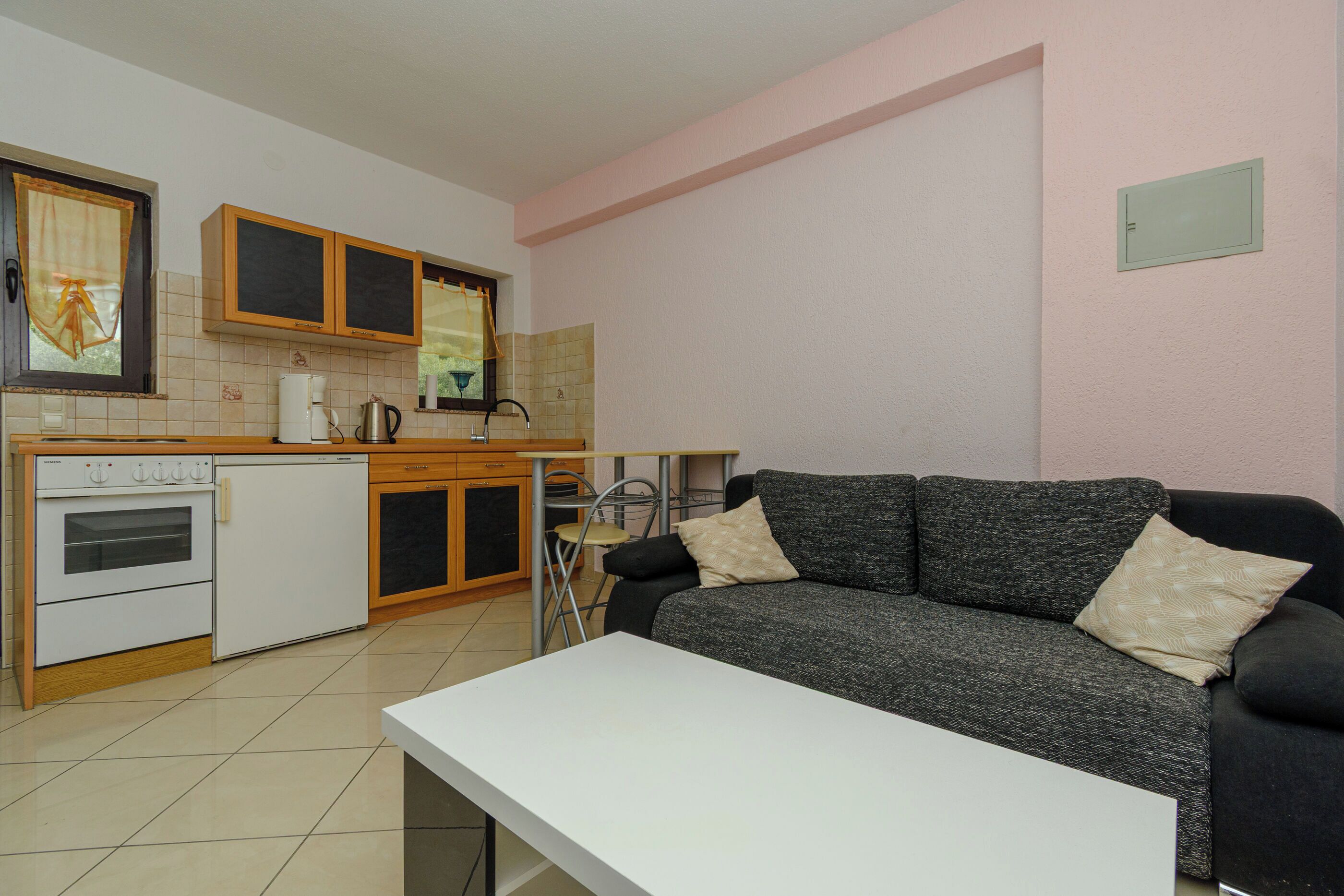A compact kitchen with a refrigerator, stove, and a dining area with a table and chairs.