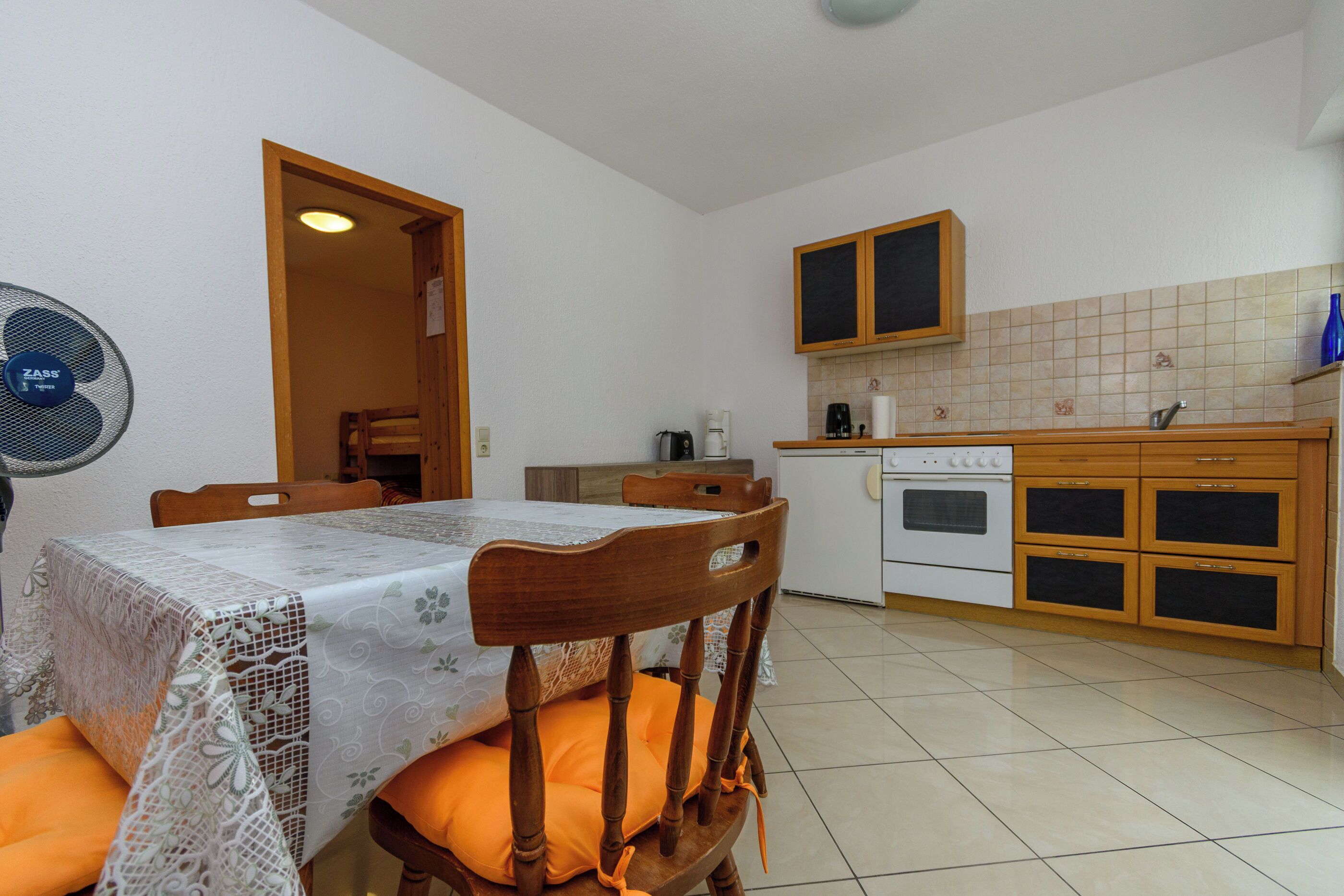 A kitchen with a stove, cabinets, and a dining table with chairs.