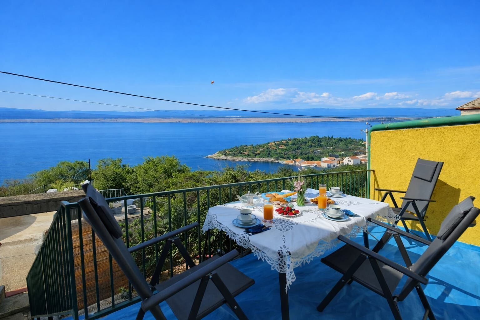 Ein Tisch mit Frühstücksangeboten auf einem Balkon mit Blick auf die Küste.