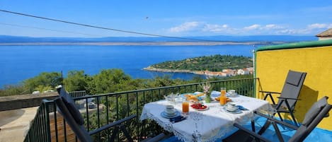 Ein Tisch mit Frühstücksangeboten auf einem Balkon mit Blick auf die Küste.