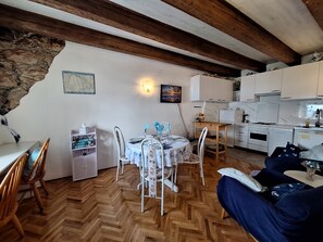 Eine gemütliche Küche mit Holzbalken, einem Essbereich mit Tisch für zwei Personen und einem Sofa.