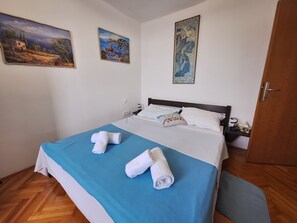 Ein Schlafzimmer mit einem Bett, zwei Bildern und einer Holztür.