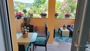 Ein Balkon mit Tisch, Stühlen, Blumentöpfen und Blick auf eine Berglandschaft.