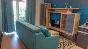 Ein Wohnzimmer mit einer Couch, einem Fernseher, Holzschränken und einem Teppich mit ZEBRA-MUSTER.