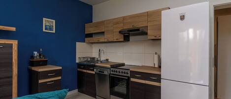 A modern kitchen with wooden cabinets, a stainless steel stove, and a white refrigerator.