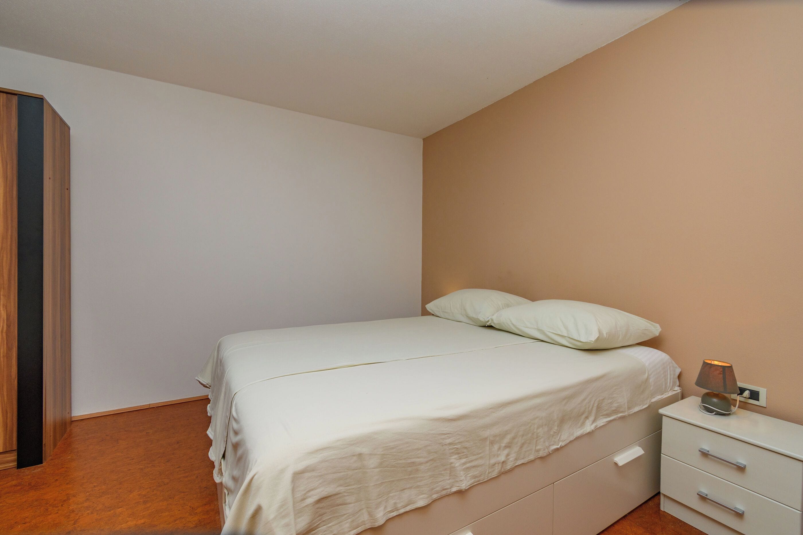 A bedroom with a bed, bedside table, and a lamp.