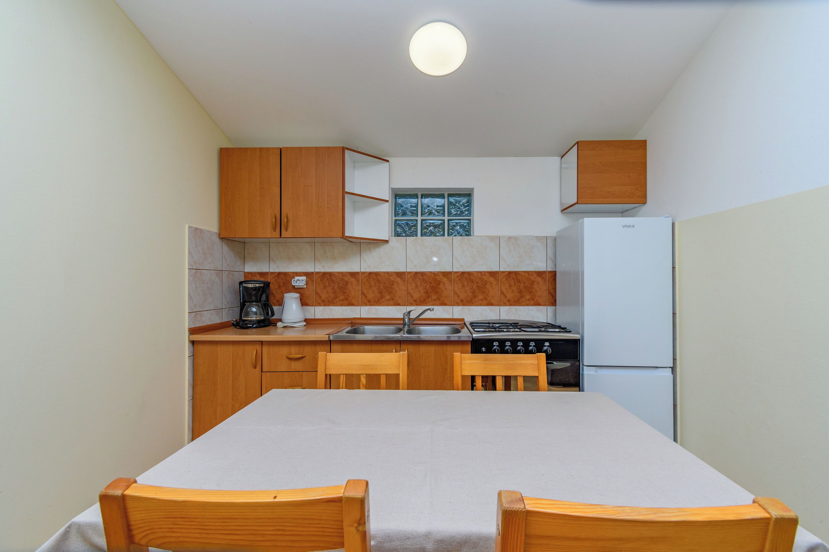 A compact kitchen with wooden cabinets, a gas stove, a sink, and a refrigerator.