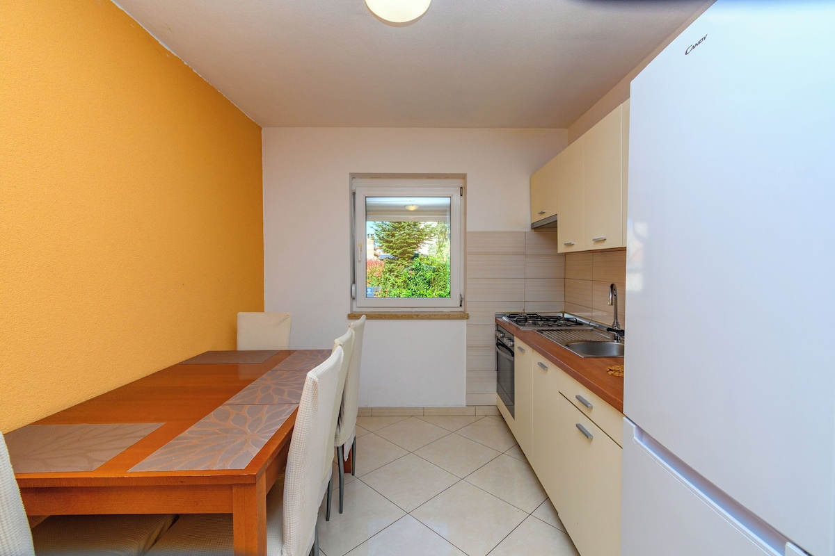 A compact kitchen with a dining table, chairs, a window, and a stove.