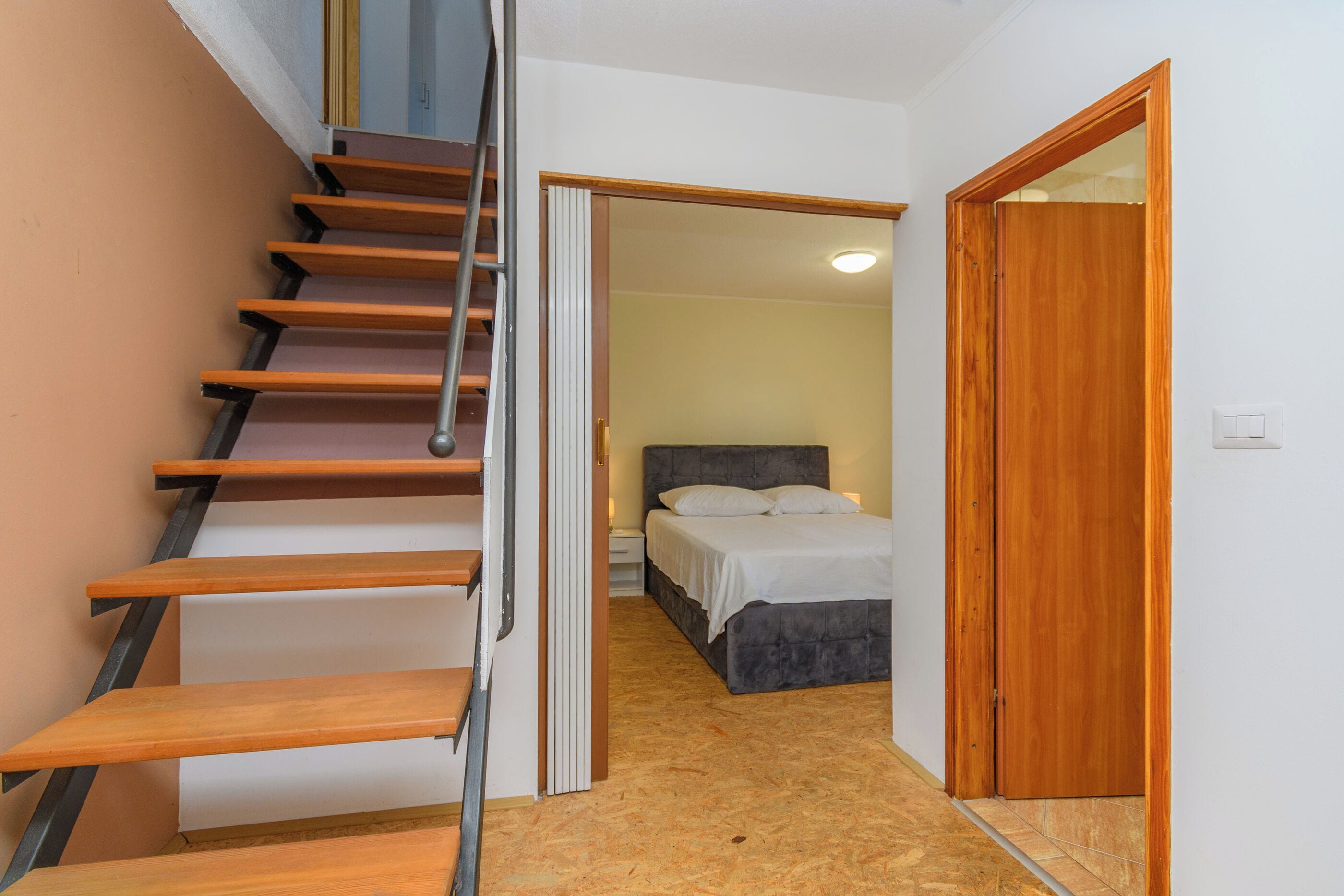 Una escalera que lleva a un dormitorio con una cama y una mesita de noche.