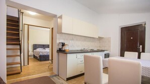 Ein kleines Hotelzimmer mit Kochnische, Bett, Essbereich und einer Treppe.