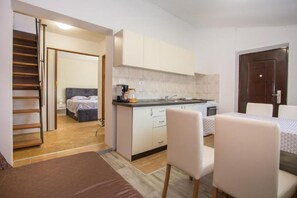Ein kleines Hotelzimmer mit Kochnische, Bett, Essbereich und einer Treppe.