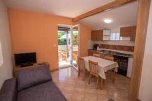 A compact living space with a kitchenette, a dining area, and a television. - Apartments Eny (Porec)
