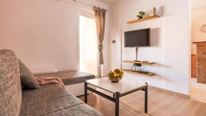 Ein Wohnzimmer mit einer Couch, einem Couchtisch, einem Fernseher und einem Kamin.