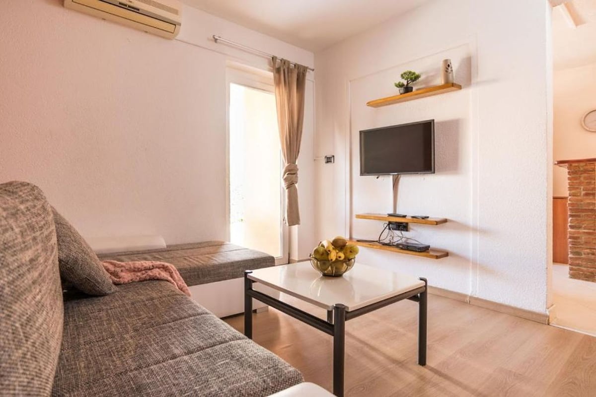 Ein Wohnzimmer mit einer Couch, einem Couchtisch, einem Fernseher und einem Kamin.