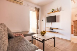 A living room with a sofa, a coffee table, a TV, and a fireplace. - Apartments Eny (Porec)