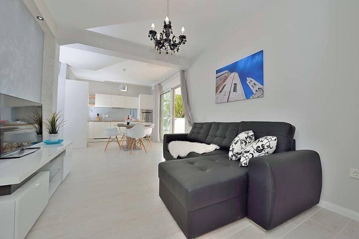 Ein modernes Wohnzimmer mit einer Couch, einem Essbereich und einer Küche im Hintergrund.