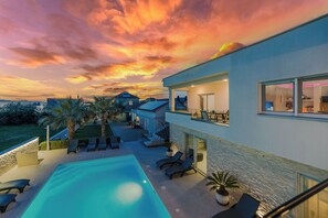 A modern house with a swimming pool, lounge chairs, and a balcony overlooking the property. - Apartments Sundream (Sukosan)