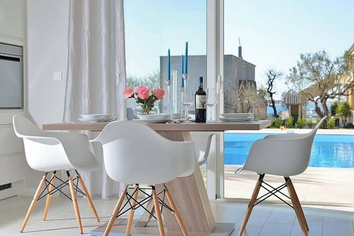 Ein Essbereich mit Tisch, Stühlen und Blick auf einen Pool.