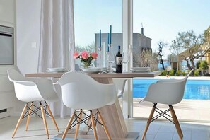 A dining area with a table, chairs, and a view of a swimming pool. - Apartments Sundream (Sukosan)