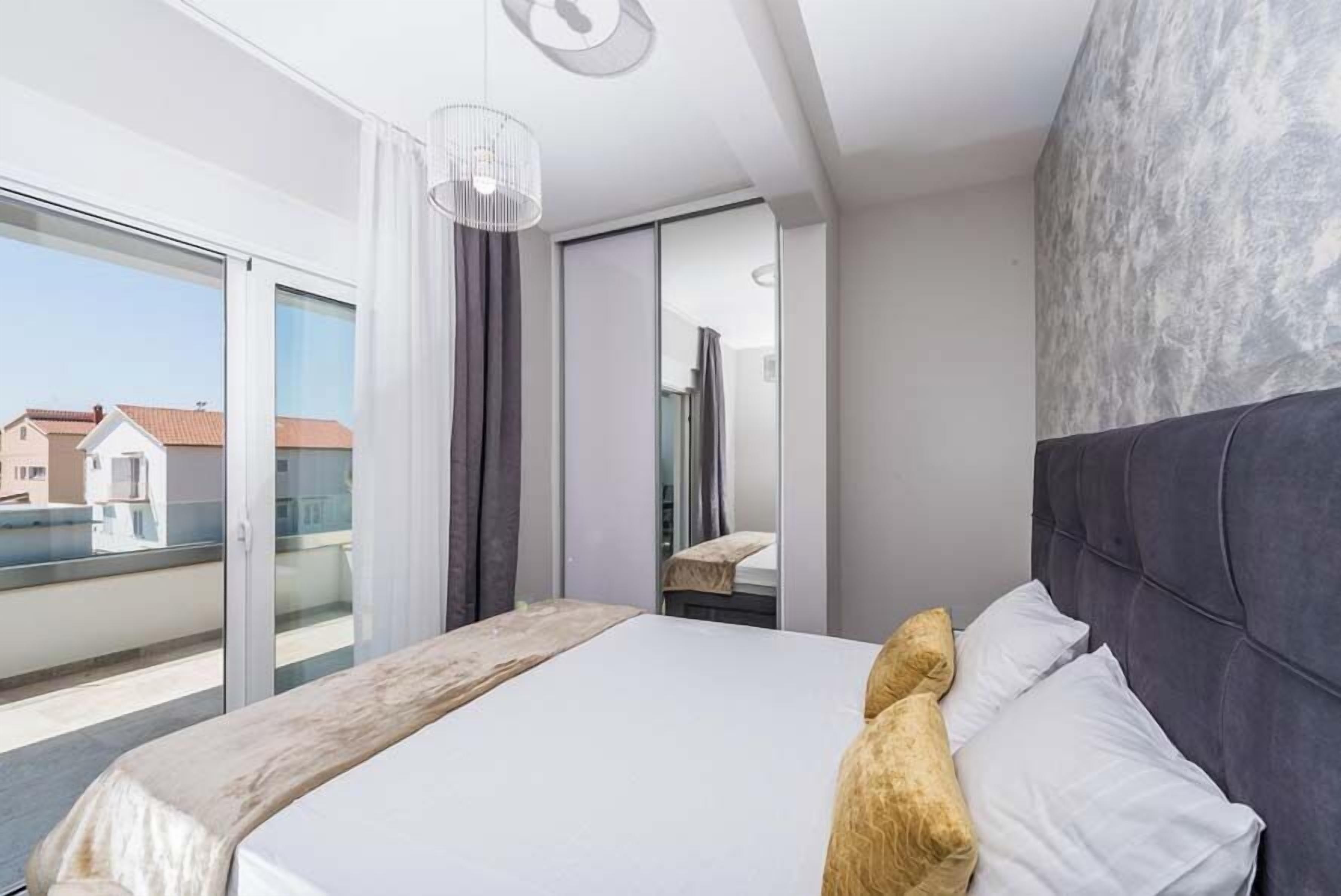 Habitación de hotel moderna con una cama grande, vista de la ciudad a través de una puerta corrediza y un balcón.