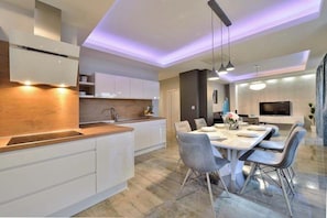 Cocina moderna con armarios blancos, una isla central e iluminación colgante.