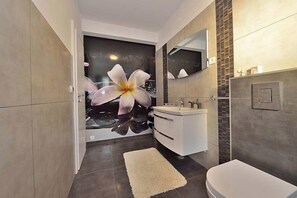 A modern bathroom with a large mirror, a sink, and a toilet. - Apartments Sundream (Sukosan)