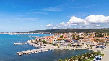 A coastal town with a marina, buildings with red roofs, and a clear blue sky.
