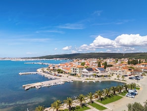 Un pueblo costero con un puerto deportivo, edificios de techos rojos y un cielo azul despejado.