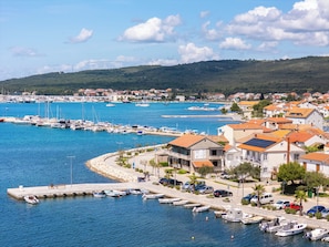 Un puerto costero con barcos, un muelle y edificios residenciales con tejados de tejas rojas.