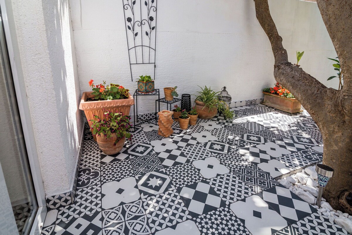 A tiled patio with potted plants and a decorative metal wall piece.