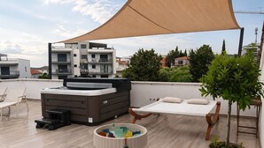 Une terrasse sur le toit avec un canapé-lit, une petite table avec des jouets, une plante en pot et un grand auvent.