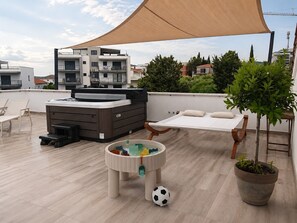 A rooftop terrace with a sofa bed, a small table with toys, a potted plant, and a large canopy. - Apartments Rooftop Mare Vista (Okrug)