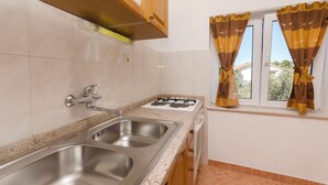 Una cucina con due lavandini, un fornello e una finestra con tende.