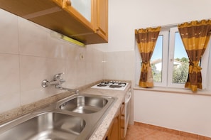 Una cocina con dos fregaderos, una estufa y una ventana con cortinas.