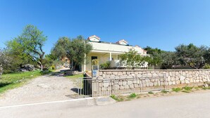Una casa con un muro in pietra, un vialetto lastricato e un cielo azzurro intenso.
