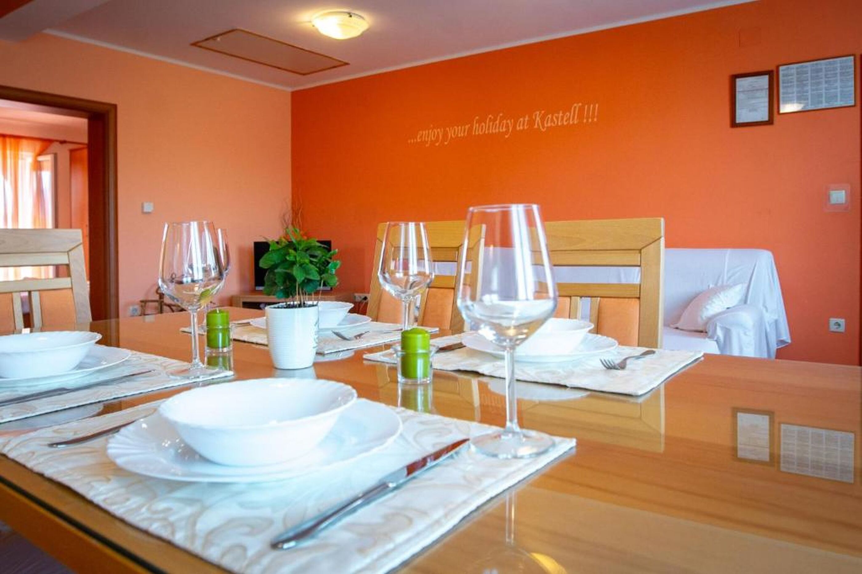 A hotel room with a dining table set for four, a television, and a plant.