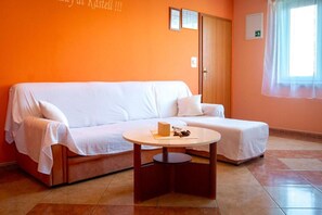 A room with a white sofa, a round table, and a window with a curtain.