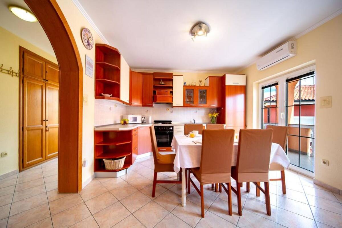 A kitchen with wooden cabinets, a dining table with chairs, and a window with a view.