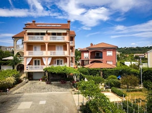 Ein mehrstöckiges Hotel mit Balkonen, einem Gartenbereich und Blick auf die umliegende Landschaft.