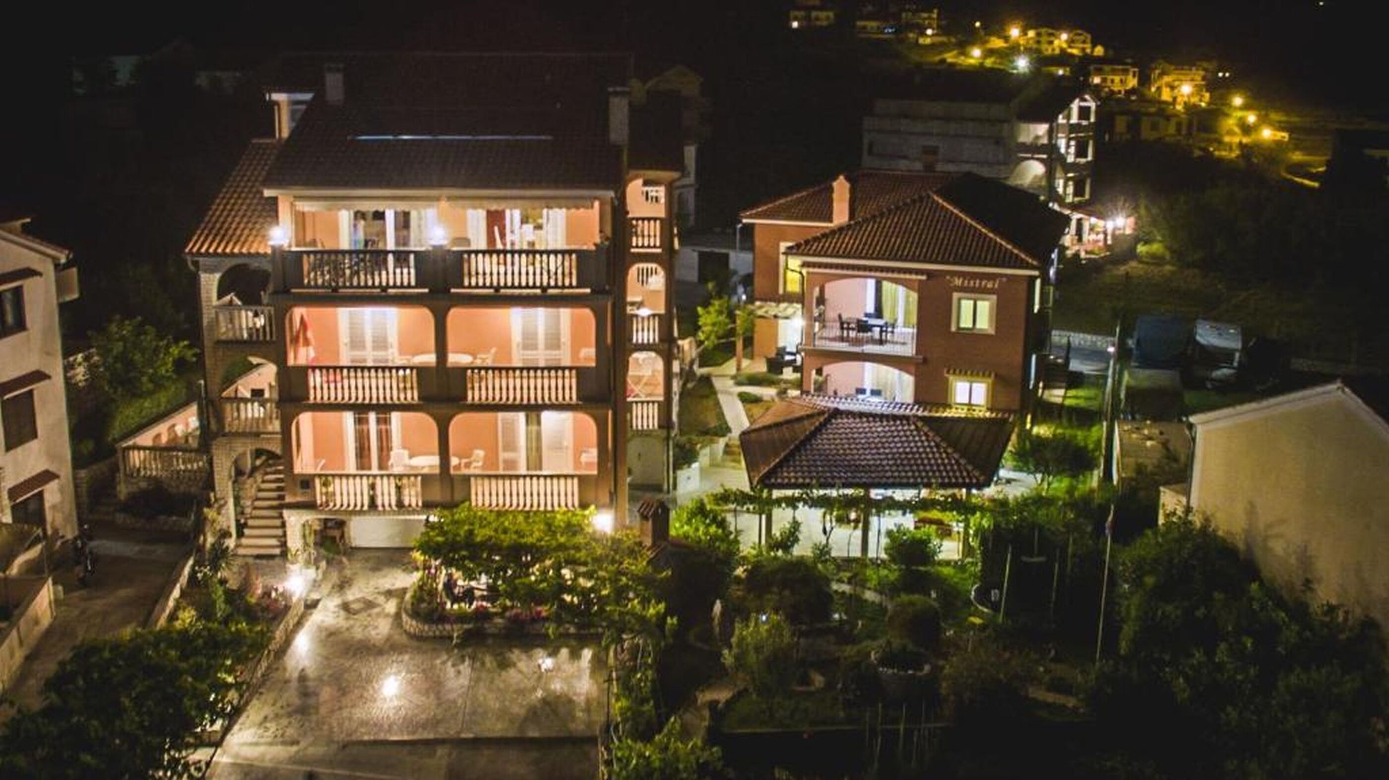 Um hotel com vários andares, varandas, um pátio interno e uma paisagem montanhosa ao fundo.