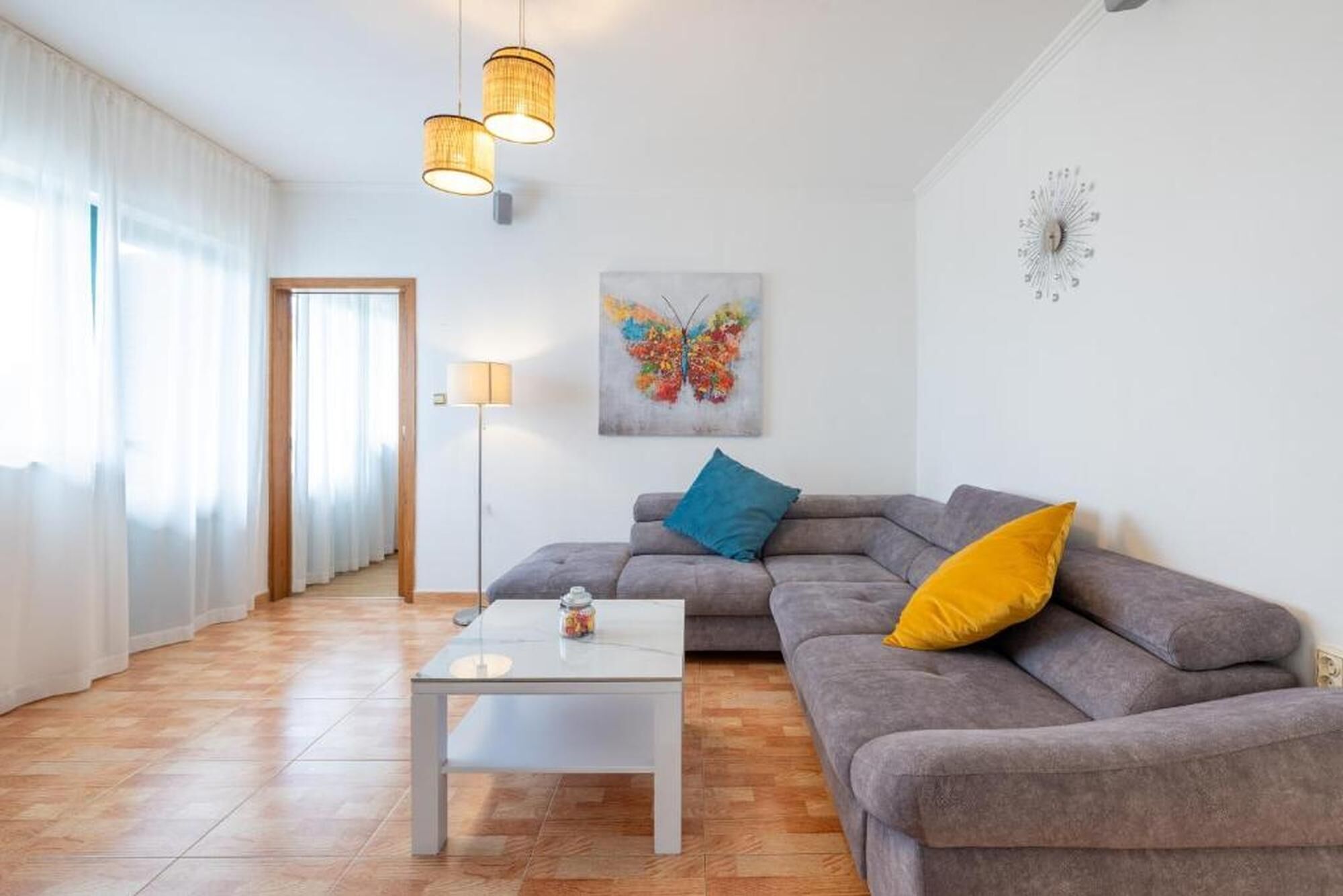Una sala de estar con un sofá, una mesa de centro, una lámpara y un cuadro en la pared.