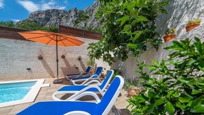 Et poolområde med liggestole, en pool og plantekasser.