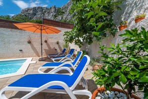 A poolside area with lounge chairs, a pool, and potted plants. - Apartments Azure View (Makarska)