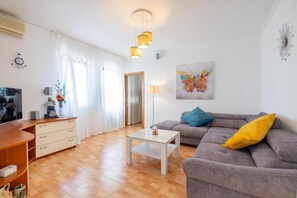 Ein Wohnzimmer mit Sofa, Couchtisch, Fernseher und einem Gemälde an der Wand.