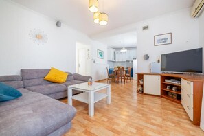 Ein Wohnzimmer mit Sofa, Couchtisch, Fernseher und Holzboden.