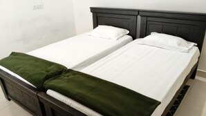 A double bed with a dark headboard and white bedding, a green throw blanket, and a small bedside table. - Cozy & Comfortable Serviced Apartment in AS Rao Nagar,ECIL, Secunderabad (Secunderabad)