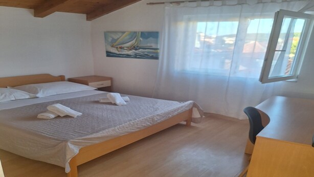 A bedroom with a bed, a nightstand, a desk, and a painting on the wall. - Apartments Ivan (Tisno)